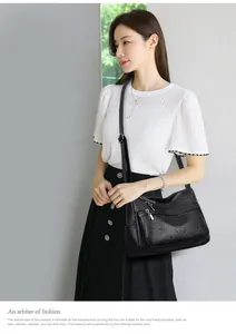Mannequin asiatique portant un sac à bandoulière en cuir noir avec motif trèfle et zips.