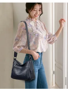 Sac bandoulière bleu marine pour femme avec motif trèfle élégant sur mannequin.