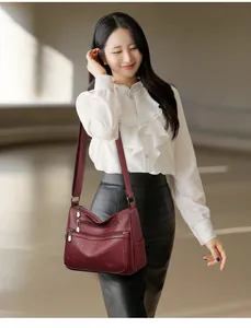 Sac à bandoulière bordeaux élégant avec motifs trèfle à quatre feuilles gaufrés sur mannequin.