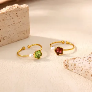 Macro view of gold plated flower rings with green and red zircon stones and pearls
