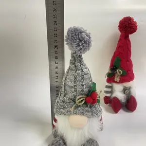 Detailopname van een 27 cm hoge gebreide kerstkabouterpop naast een meetlat.