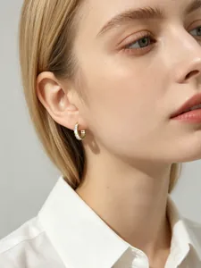 Close-up of a professional model wearing elegant square baguette-cut zircon silver hoop earrings.