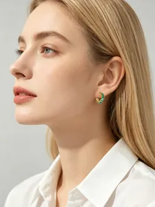 Close-up of elegant gold hoop earrings with square-cut emerald green zircons on model