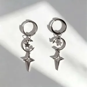 Detail shot of gothic punk dangle earrings with crescent moon and four-pointed star pendants.