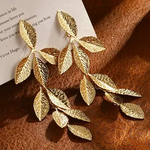 Close-up detail of golden textured leaf-shaped long drop earrings in vintage style