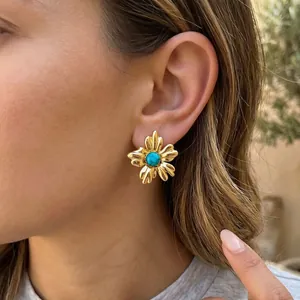 Gros plan détaillé de boucles d'oreilles fleurs dorées avec turquoise sur le modèle
