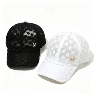 Détail de casquettes de baseball en dentelle noire et blanche avec logo M en métal doré