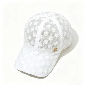Détail de casquette en dentelle blanche avec broderie florale et badge métallique doré H