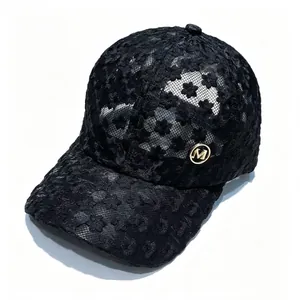 Vue détaillée d'une casquette de baseball en dentelle florale noire avec emblème doré du logo M