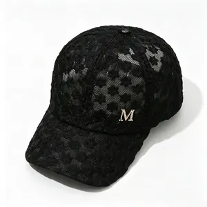 Détail d'une casquette de baseball en dentelle noire avec logo M en strass brillant