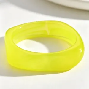 Close-up view of a translucent lime yellow irregular resin bangle with wave-like edges