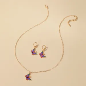 Detailed view of colorful butterfly jewelry set with gold necklace and hoop earrings