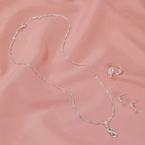 Elegant silver infinity jewelry set including necklace, ring and earrings on pink silk fabric.