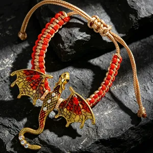 Detalle de pulsera tejida vintage con un amuleto de dragón de esmalte dorado y joyas