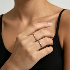 Detailansicht von minimalistischen Gold- und Silberringen aus Edelstahl am Finger.