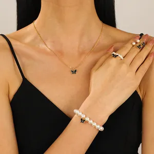 Elegante juego de joyas de 4 piezas con mariposas negras y perlas blancas en una modelo
