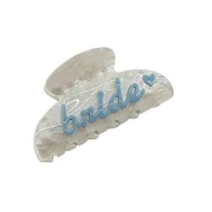 Détail d'une pince à cheveux Bride blanc nacré avec une écriture bleue et un cœur.