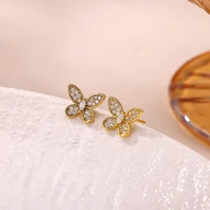 Close-up of golden butterfly stud earrings with sparkling pavé zircon stones