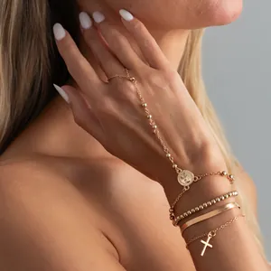 Detailansicht eines goldenen Handketten-Armbands mit Münz- und Kreuzanhängern.