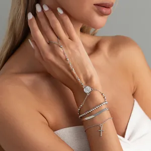 Detailaufnahme eines silbernen mehrlagigen Ring-Armbands mit Kreuz und Münze