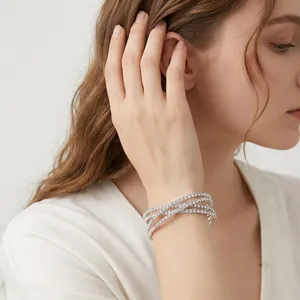 Close-up of a model wearing an elegant silver-toned rhinestone double-layer cross bracelet