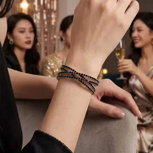 Detail shot of a black rhinestone double-layer cross bracelet on a woman's wrist