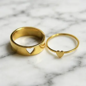 Primer plano detallado de anillos de pareja bañados en oro de 18 quilates con corazones.