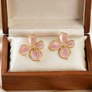 Elegant close-up of pink enamel cherry blossom stud earrings inside a wooden gift box.