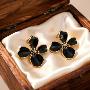 Close-up view of vintage black enamel flower earrings presented in a wooden jewelry box