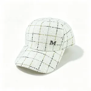 Gros plan sur une casquette en tweed blanc à carreaux avec un emblème M argenté