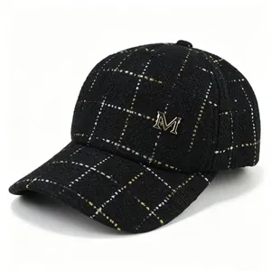 Vue détaillée d'une casquette de baseball en tweed noir avec logo M doré et quadrillage