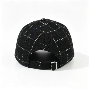 Vue arrière détaillée d'une casquette en tweed noir avec boucle de réglage métallique.