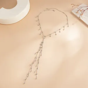 Vue de dessus d'un collier à pompons argentés avec perles métalliques sur fond beige