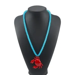 Dettaglio collana boho con perline azzurre e ciondolo a forma di granchio rosso