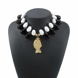 Dettaglio collana boho mare con perline bianche e nere e ciondolo a forma di pesce d'oro