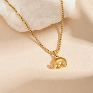 Detail view of a vintage gold-plated stainless steel elephant pendant necklace on a stone.