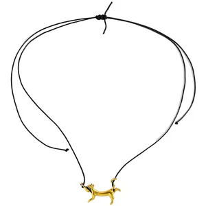 Detailansicht eines goldenen Anhängers in Form einer gehenden Katze an einer schwarzen Schnur