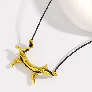 Nahaufnahme eines goldenen Katzenanhängers aus Edelstahl an einer schwarzen Kordel.