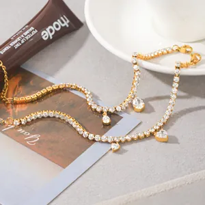 Detailopname van 18K vergulde armband met hart- en druppelvormige zirkonia-bedeltjes.