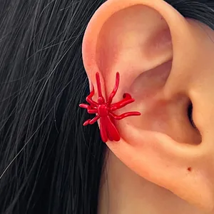 Close-up detail view of a vibrant red spider-shaped ear cuff on a female model's ear bone.