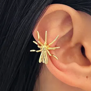 Detail view of a gold spider-shaped ear cuff worn on the ear, gothic Halloween jewelry.