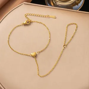 Close-up of a gold-plated stainless steel heart finger bracelet on a beige display