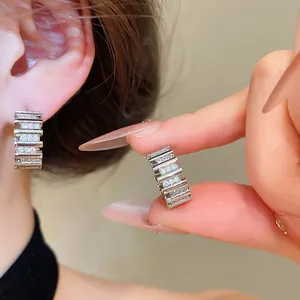 Vista detallada de elegantes pendientes de circonita bañados en plata 18k con diseño de barra.