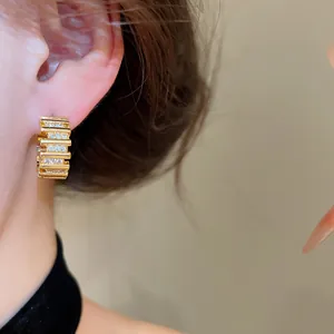 Primer plano de pendientes de aro chapados en oro de 18k con circonitas en la oreja