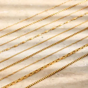 Close-up of various 18K gold plated stainless steel necklace chains on textured stone