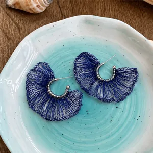 Pendientes de botón en forma de abanico de malla azul en un plato decorativo