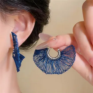 Detalle de los pendientes de abanico en hilo tejido azul con diseño intrincado.