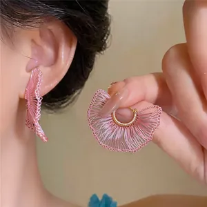 Vista detallada de delicados pendientes de encaje tejido rosa en el oído del modelo