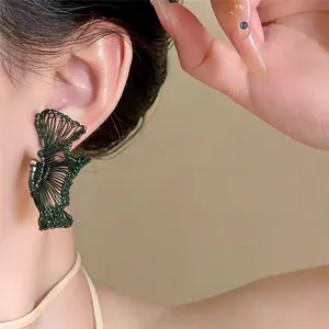 Detalle de un pendiente en forma de abanico envuelto en alambre verde oscuro en la oreja