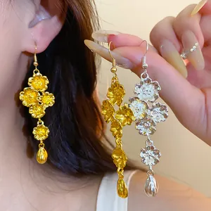 Dettaglio di eleganti orecchini a fiori oro e argento con pendente a goccia d'acqua